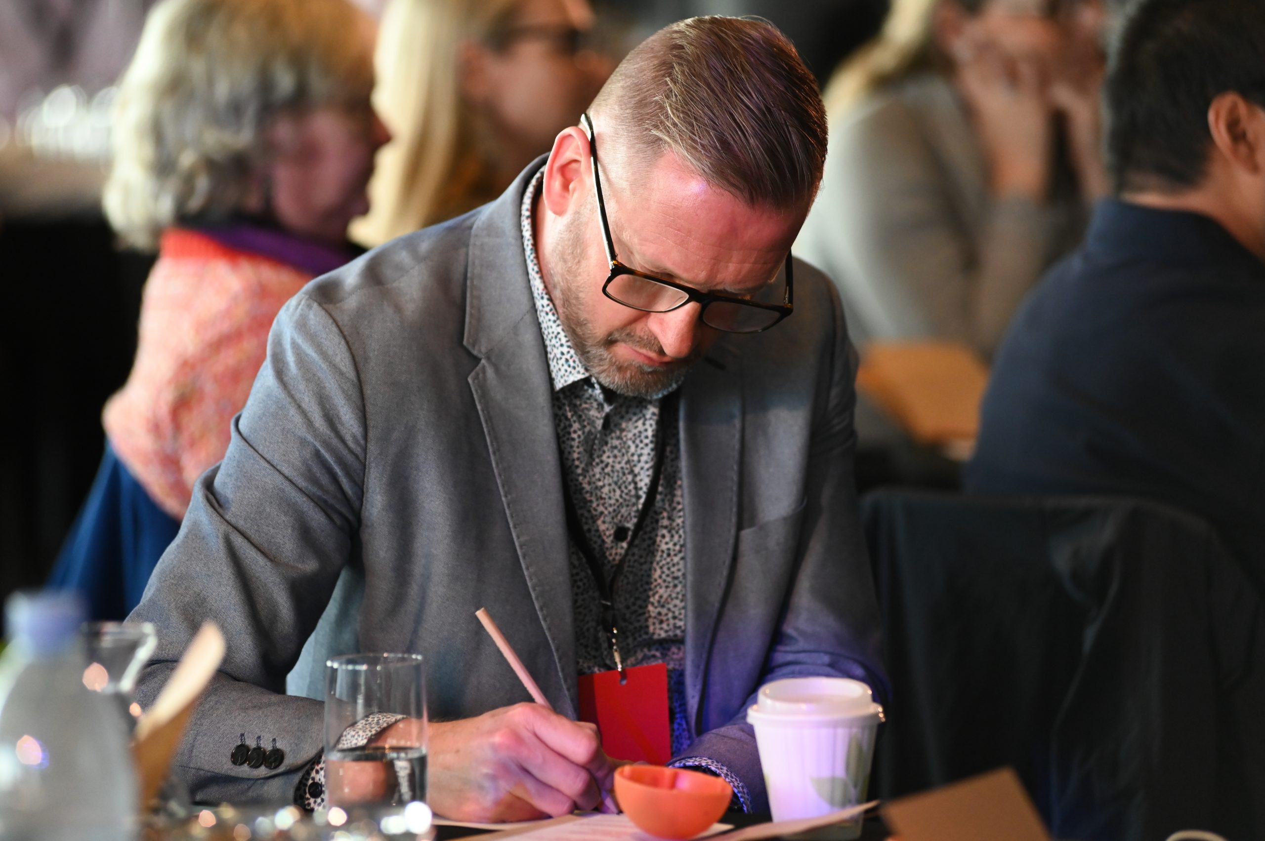 Person looking down intently as they write on a piece of paper